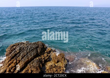 Vista pittoresca sulla roccia e le acque azzurre del Mar Mediterraneo. Spiaggia rocciosa per sfondo Foto Stock