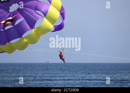 Parasailing sul mare, uomo con action camera che vola nel cielo blu, fuoco selettivo sul paracadute. Concetto di vacanza, sport estremi su una spiaggia Foto Stock