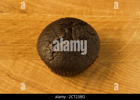 Un cupcake color caffè si trova su un asse di legno Foto Stock