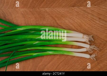 Bouquet di cipolle verdi fresche su tavola di legno. Cibo vegetariano sano. Primo piano. Vista dall'alto Foto Stock