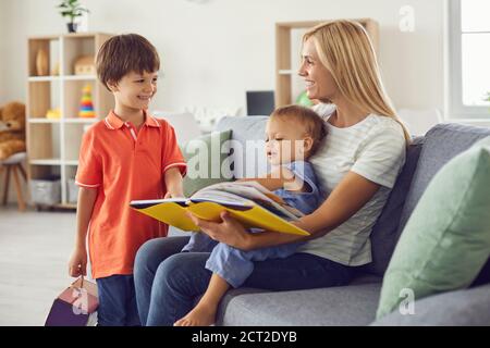 Buon libro di lettura della mamma delle fiabe al suo piccolo i bambini si siedono su un comodo divano a casa Foto Stock