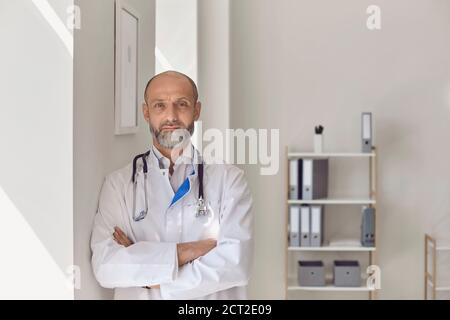 Il medico sta guardando la macchina fotografica mentre sta in piedi nell'ufficio della clinica. Foto Stock