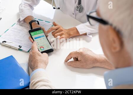 Mani di giovane nutrizionista femminile che mostrano il suo paziente anziano importante dati Foto Stock