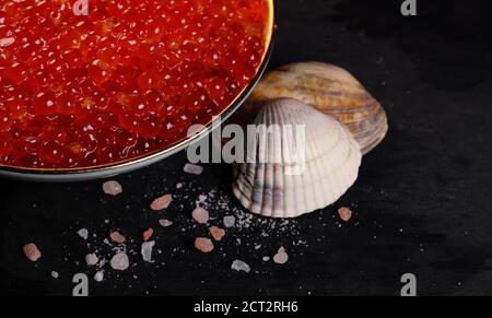 Caviale rosso in ciotola su superficie di granito. Foto Stock