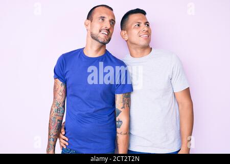 Giovane coppia gay di due uomini che indossano abiti casual guardando da parte con sorriso sul viso, espressione naturale. Ridendo fiducioso. Foto Stock