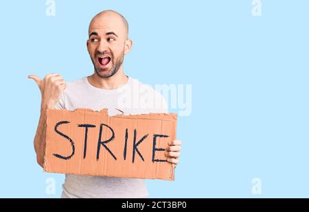 Giovane bell'uomo che tiene la bandiera di colpo che punta il pollice fino a. il lato sorridente felice con bocca aperta Foto Stock