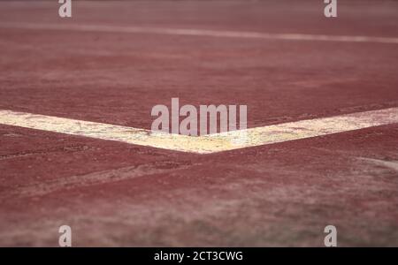 dettaglio di alcune linee bianche e gialle dipinte su a. campo sportivo marrone Foto Stock