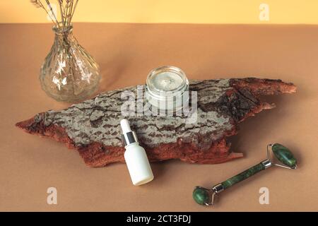 Accessori cosmetici e prodotti per la cura della pelle su corteccia di albero. Concetto di cosmetica naturale. Sfondo marrone chiaro, vista dall'alto Foto Stock