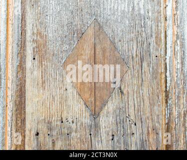 trama di sfondo-primo piano di una rustica porta di legno intemperie con una forma a rombo al centro Foto Stock