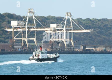 Barca pilota del porto Lufana che naviga oltre il terminal per la movimentazione del carbone, Durban, Sudafrica, servizio di navigazione marittima, paesaggio, trasporto, persone Foto Stock