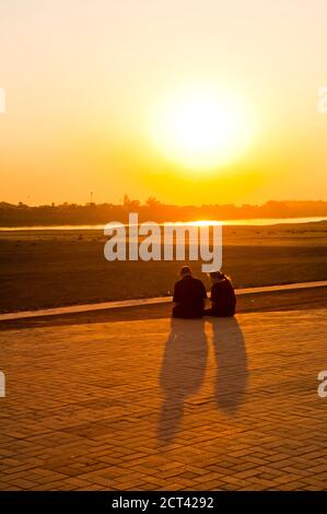 Una coppia turistica che guarda il tramonto sulla Thailandia e il fiume Mekong da Vientiane, Laos, Sud-est asiatico Foto Stock