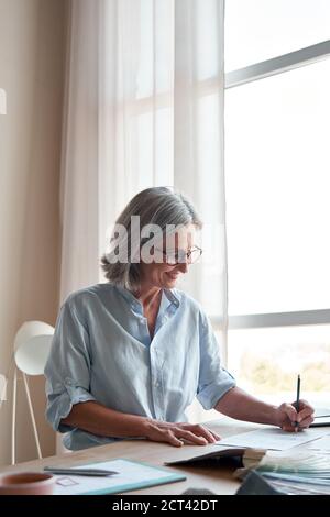 Sorridente maturo elegante donna stilista disegni schizzi in studio moderno. Foto Stock