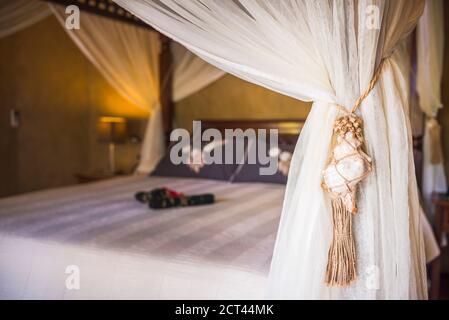 Sistemazione di lusso hotel camera dettagli di un letto a baldacchino e fiori disposti pronti per gli ospiti di arrivare, muri, Rarotonga, Isole Cook Foto Stock