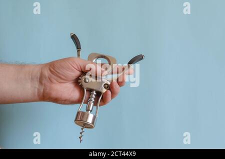 L'uomo adulto tiene in mano un cavatappi di metallo. Stappatura di bottiglie di vino. Maschio di razza europea, 43-45 anni. Utensili da cucina Foto Stock