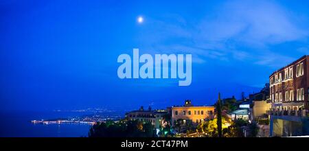 Il vulcano Etna e la luna di notte, vista panoramica vista da Piazza IX Aprile su corso Umberto, la strada principale di Taormina, Sicilia, Italia, Europa Foto Stock