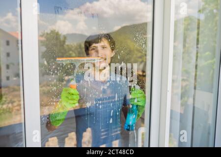 Un giovane pulisce il finestrino con un detergente per vetri Foto Stock