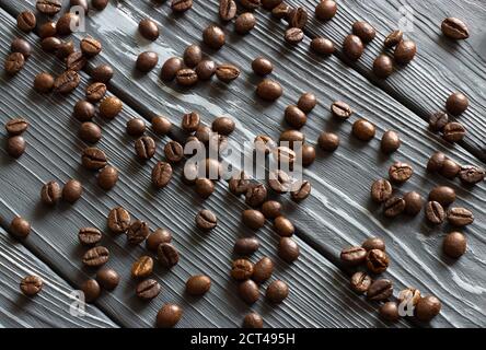 I chicchi di caffè si trovano su un tavolo di legno grigio. Trama di fondo dei chicchi di caffè Foto Stock