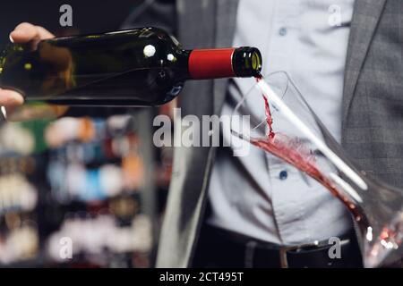 Sommelier versando vino rosso nel decanter della caraffa Foto Stock