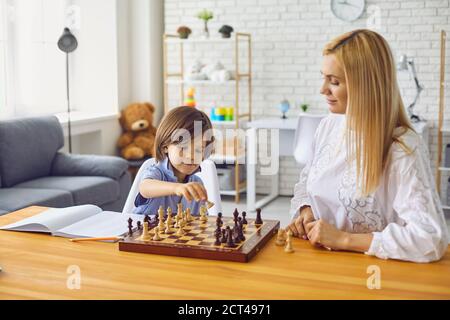 Madre e figlio giocano a scacchi al tavolo home.Happy famiglia con genitori e bambini che si divertano a giocare a tavola a casa Foto Stock