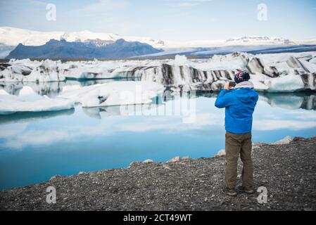 Turista scatta una foto alla Jokulsarlon Glacier Lagoon, un lago glaciale pieno di iceberg nel sud-est dell'Islanda, in Europa Foto Stock