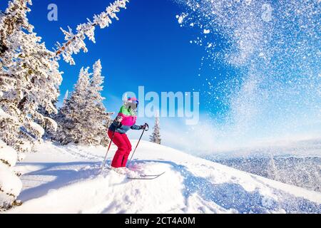 Giovane donna che salta dalla trampolino di lancio nella foresta innevata off-pista, concetto di sport estremo invernale Foto Stock
