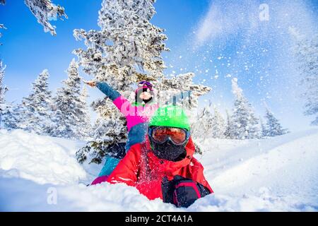 Giovane donna sciatore abbracca il tipo snowboarder e getta la neve. Concetto famiglia vacanze invernali attive Foto Stock