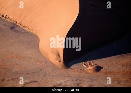 Astratto contrastato delle dune di sabbia rossa ricche di ossidi nel grande mare di sabbia della Namibia. Foto Stock