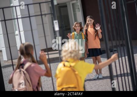 Scolari che lasciano la scuola dopo le lezioni e in attesa di amici Foto Stock