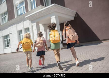 Bambini con zaini sulla strada per le lezioni Foto Stock