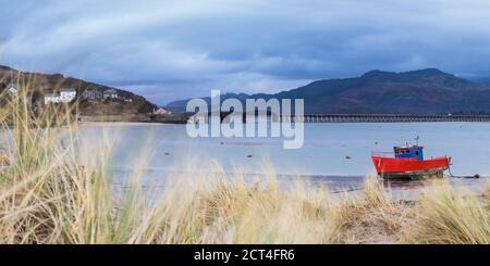 Vecchia barca da pesca e Barmouth Bridge nel porto di Barmouth con le montagne Cader (Cadair) dietro (parte del Parco Nazionale di Snowdonia), Gwynedd, Galles del Nord, Galles, Regno Unito, Europa Foto Stock