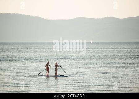 Stand up paddle boarding sul Lago di Bracciano al tramonto, Aguillara Sabazia, Provincia di Roma, Italia, sfondo con spazio copia Foto Stock