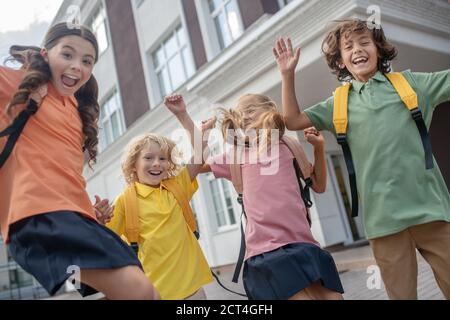 Scolari che giocano nel cortile della scuola e che guardano eccitato Foto Stock