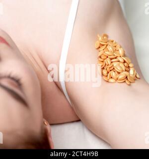 Fagioli di cera d'arancia su ascella di giovane donna caucasica. Concetto di depilazione Foto Stock