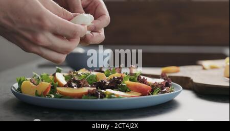 uomo facendo insalata con nettarine e mozzarella su un piatto blu su cemento piano in cucina, aggiungere mozzarella , foto ampia Foto Stock