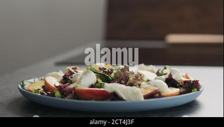 insalata con nettarine e mozzarella su un piatto blu su piano in cemento in cucina , ampia foto Foto Stock