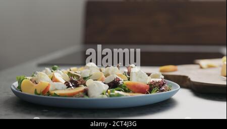 insalata con nettarine e mozzarella su un piatto blu su piano in cemento in cucina , ampia foto Foto Stock