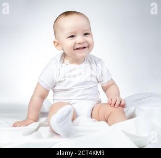 Foto di un bambino di undici mesi seduto su uno sfondo bianco Foto Stock
