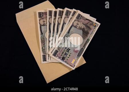 Valuta giapponese 100,000 yen con busta su sfondo nero Foto Stock