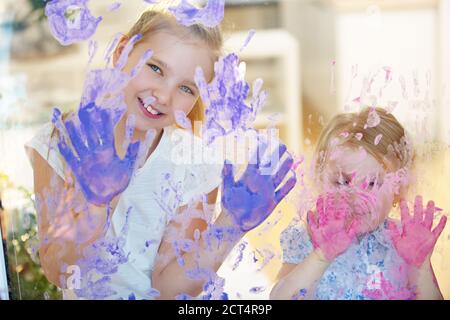 Due ragazze dipingono molte stampe su un pannello con il dito vernice Foto Stock