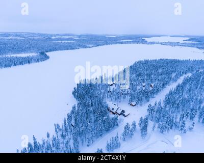 Foto di droni aerei di cabine, capanne e alloggi nella foresta, con neve coperta paesaggio invernale e alberi in boschi, Torassieppi, circolo artico in Lapponia finlandese, Finlandia Foto Stock