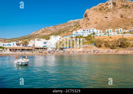 Piccola spiaggia di sabbia del villaggio di Finiki con taverne sullo sfondo, Isola di Karpathos, Grecia Foto Stock