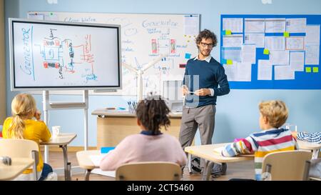 L'insegnante di fisica della scuola elementare usa la lavagna interattiva digitale per mostrare In un'aula piena di bambini intelligenti e diversificati come rinnovabili Energia funziona Foto Stock