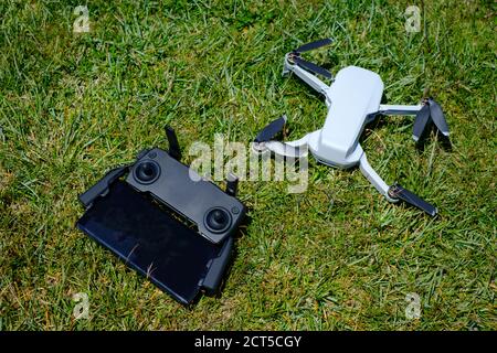 Mini drone portatile con telecomando collegato a a. smartphone su sfondo erboso Foto Stock