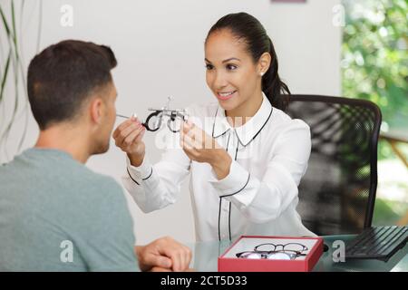 oftalmologo che aiuta il paziente di sesso maschile a scegliere gli occhiali in ottica Foto Stock