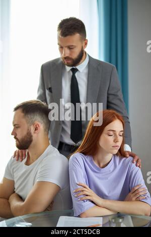 psicologo fiducioso ascoltare i problemi della coppia, cercare di aiutare e dare consigli su come risolvere i loro problemi, fare la pace. uomo e donna sono offesi a. Foto Stock