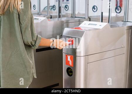 Donna irriconoscibile che mette la carta nella macchina del cancello e che compra il biglietto sulla moderna stazione ferroviaria Foto Stock