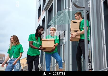 diversi volontari si impacchettano, raccolgono aiuti umanitari in una scatola di donazione. gruppo multietnico di persone che lavorano in fondazione caritatevole aiutando in cris Foto Stock