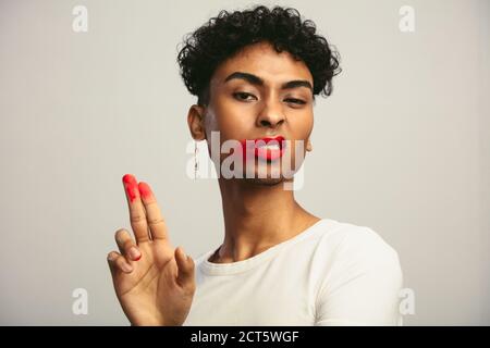 Uomo gay con rossetto rosso sbavato che mostra le dita e fa il viso disgustoso. Foto Stock