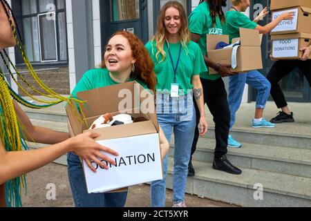 diversi volontari si impacchettano, raccolgono aiuti umanitari in una scatola di donazione. gruppo multietnico di persone che lavorano in fondazione caritatevole aiutando in cris Foto Stock
