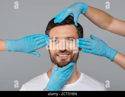Mani in guanti protettivi che toccano il volto sorridente dell'uomo Foto Stock
